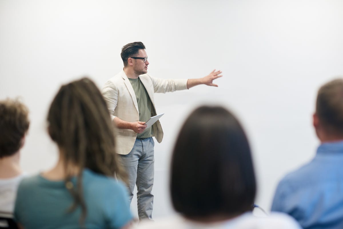 Professional trainer presenting with tablet to engaged audience in modern training environment